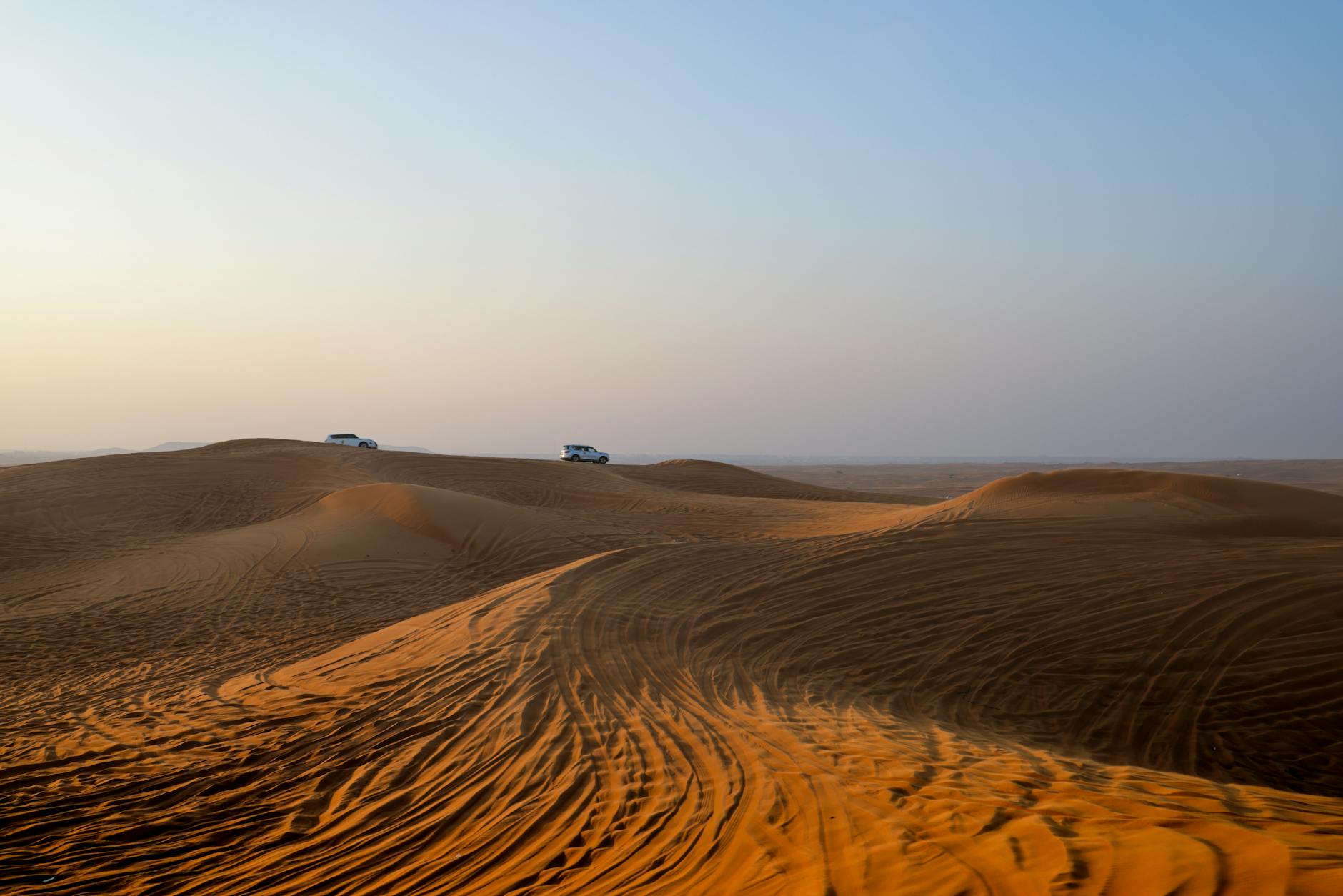 Traversing the serene desert dunes by car, capturing the essence of a desert safari at dawn.